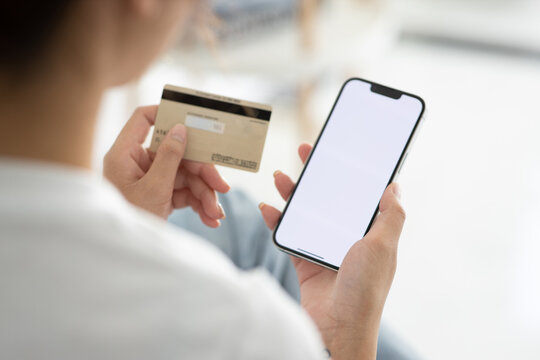 A close-up photo of a young woman using her smartphone and her credit card at home. Online shopping ( credit card mockup )