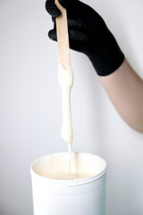 Sugar depilation. A piece of sugar paste dripping from a wooden spatula