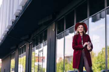 Outdoor autumn portrait of young elegant fashionable woman wearing trendy coat, leather shoulder bag.