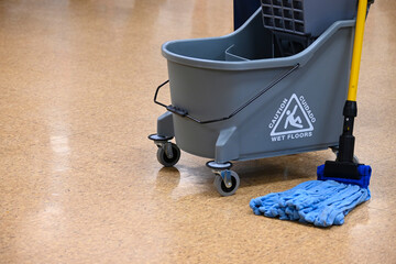 Microfiber mop and double bucket on shiny floor. Custodial activities. Floor maintenance in public...