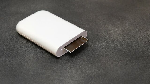 Proccess of printing photo with portable printer. Wireless mini printer for smartphones. Small prints for a photo album