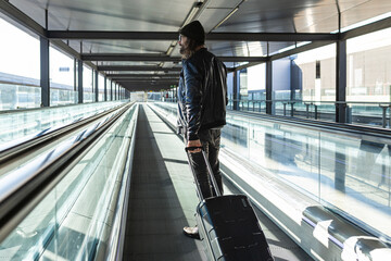 Hipster male traveler on treadmill in airport