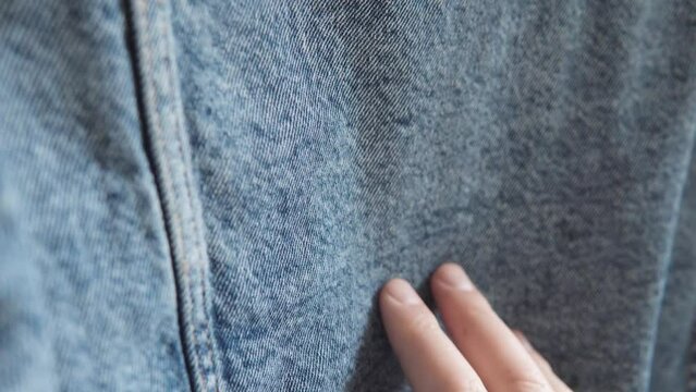 A garment factory worker evaluates the quality of denim fabric in a textile factory.