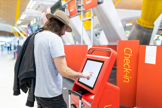 Bearded man using self check in machine at airport