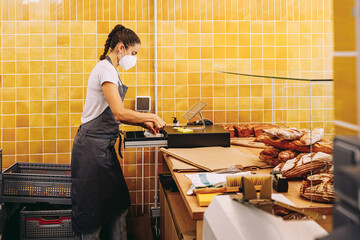 Female seller at cash register in bakery