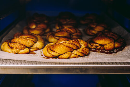 Tasty cinnamon buns on baking paper in oven