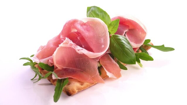 R&auml;ucherschinken Scheiben auf Kn&auml;ckebrot - Roher Schinken mit Basilikum freigestellt auf wei&szlig;em Hintergrund