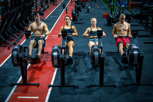 Group of sporty people working out on the rowing machines at the gym.