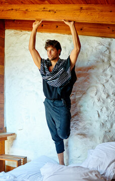 Stylish Hispanic model with raised arms on bed