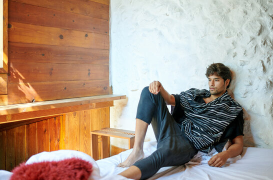 Trendy ethnic model resting on bed in countryside house