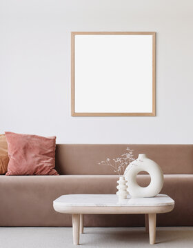 Blank frame mockup in modern interior design with trendy vase and sofa on empty white wall background, Square template for paintings, photo or poster. Artwork mock-up.