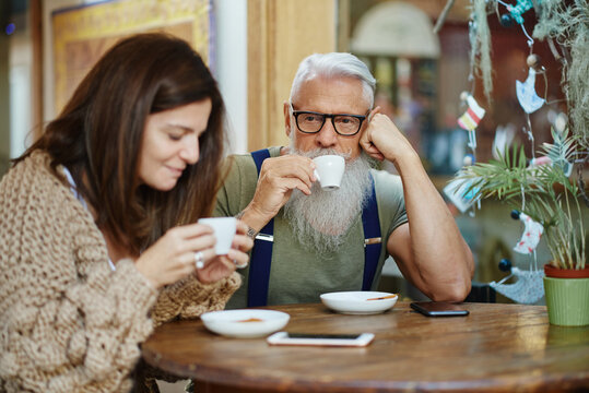 Hipster grandfather with granddaughter drinking coffee at cafe