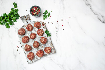 Fototapeta na wymiar Raw meatballs minced pork on a light background, banner, menu, recipe place for text, top view