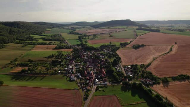 Aer ial view of a German village surrounded by meadows, farmland and forest in Germany.