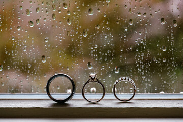 Three wedding rings in front of rainy window