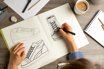 The artist designer draws a sketch of shoes on paper. - 527886390