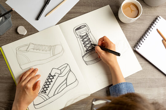 The artist designer draws a sketch of shoes on paper.