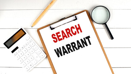 SEARCH WARRANT words on clipboard, with calculator, magnifier and pencil on the white wooden background