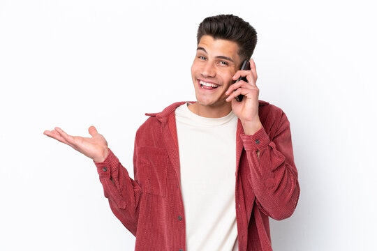 Young caucasian man isolated on white background keeping a conversation with the mobile phone with someone