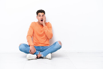 Young man sitting on the floor isolated on white background with surprise and shocked facial expression