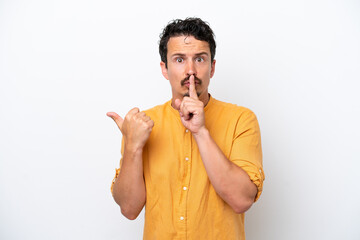 Young man with moustache isolated on white background pointing to the side and doing silence gesture
