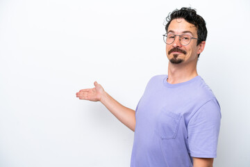 Young man with moustache isolated on white background extending hands to the side for inviting to come