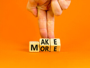 Make more symbol. Concept words Make more on wooden cubes. Businessman hand. Beautiful orange table orange background. Business, motivational quotes and Make more concept. Copy space.