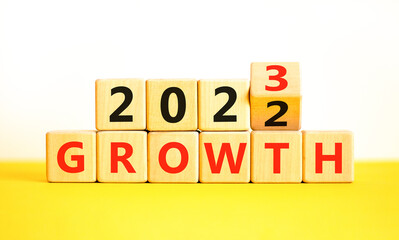 Planning 2023 growth new year symbol. Turned a wooden cube and changes words Growth 2022 to Growth 2023. Beautiful yellow table white background, copy space. Business 2023 growth new year concept.