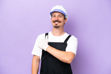 Fishmonger man wearing an apron isolated on purple background giving a thumbs up gesture