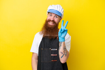 Fishmonger wearing an apron isolated on yellow background smiling and showing victory sign