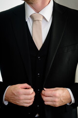 a Groom straightening his jacket with a blush tie