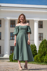 Fototapeta premium Full length portrait of a young beautiful red hair in green long dress