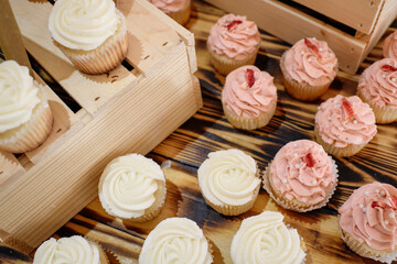 Rustic spread of pink and white buttercream cupcakes decorated with slices of fruit on wooden crates