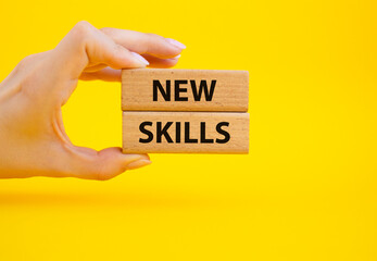 New skills symbol. Wooden blocks with words New skills. Beautiful yellow background. Businessman hand. Business and New skills concept. Copy space.