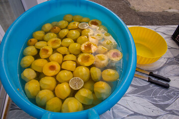 Picture of a basin with cut peaches and lemon. Preparation of peaches in syrup in jars.
