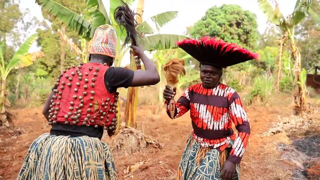 Two African dancers dance dressed in traditional clothing during a tribal event.