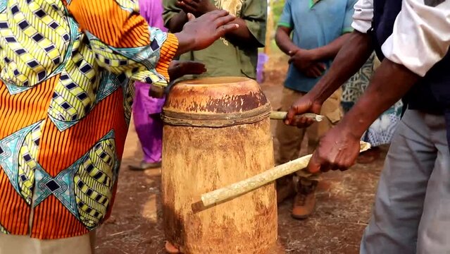 People play a drum during a funeral in an African village, tribal life Africa.