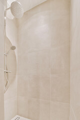Shower faucets attached to tiled wall near glass partition and ornamental curtail in washroom at...