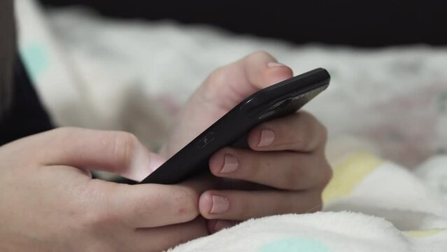 Teen girl scrolling on the news feed while laying in her bad, instead of studying