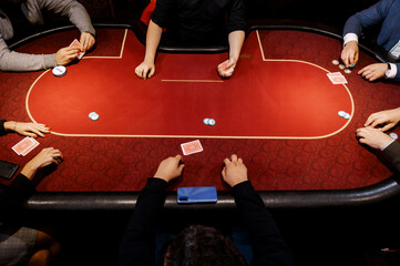 top view of men and women playing poker in casino