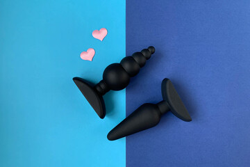 Sex shop assortment. Black butt plug. Two sex toys on a blue background