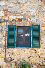 A window with green shutters on a Tuscany stone wall in the Chianti region of Tuscany, Italy, Europe.