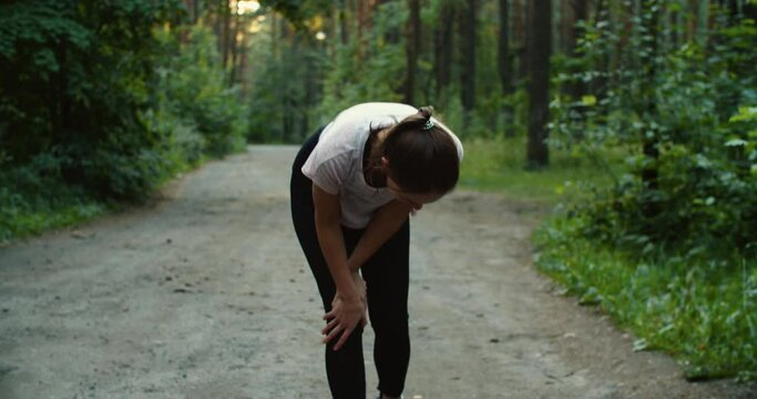 Runner complaining with knee ache after running in the woods. High quality 4k footage