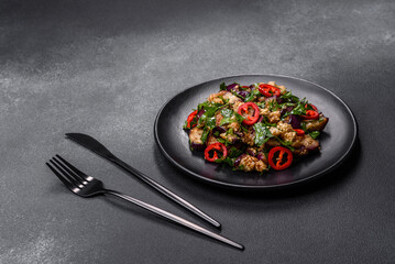 A salad of baked aubergine, sweet pepper, garlic, zucchini and parsley in a black plate