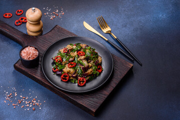 A salad of baked aubergine, sweet pepper, garlic, zucchini and parsley in a black plate