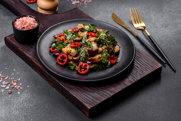 A salad of baked aubergine, sweet pepper, garlic, zucchini and parsley in a black plate