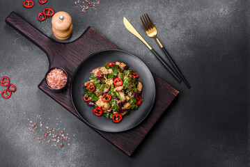 A salad of baked aubergine, sweet pepper, garlic, zucchini and parsley in a black plate