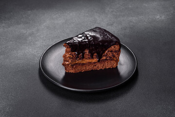 A piece of fresh delicious cake with nuts and chocolate on a black plate