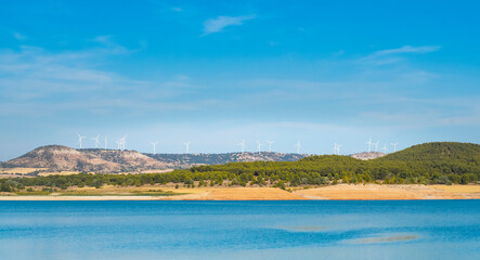 Fototapeta na wymiar Windmills over a lake with blue water