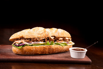 fast food beef brisket sandwich with arugula and coleslaw salad on baguette bread on wooden board...